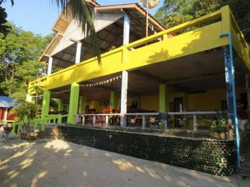 a yellow building with a palm tree in front of it at Lae Tawan Bungalow in Koh Chang Ranong