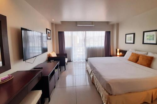 a hotel room with a large bed and a television at Grand Hotel in Pattaya South