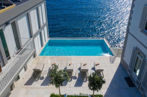 an overhead view of a swimming pool with chairs and the ocean at Luxury Barreirinha House old town by HR MADEIRA in Funchal