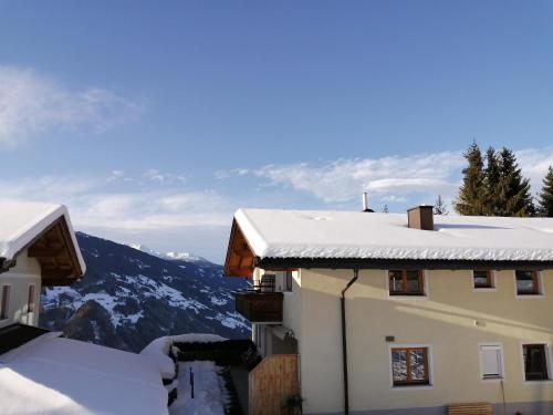 a building covered in snow with mountains in the background at Apartement Flörl in Rohrberg