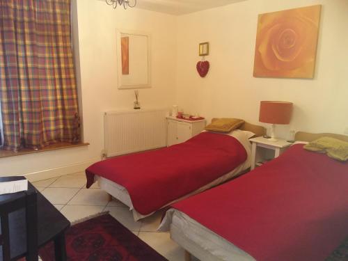 two beds in a room with red sheets at Le Patronage in Bazoges-en-Pareds