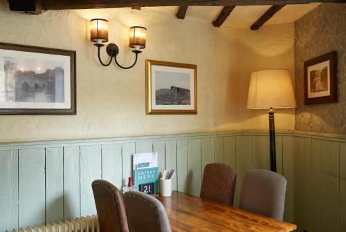 a dining room with a table and chairs and a lamp at Castle Inn by Greene King Inns in Bakewell