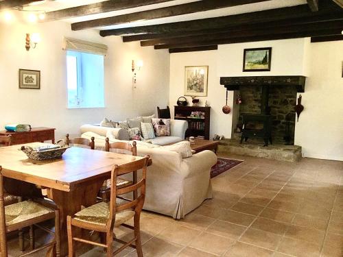 een woonkamer met een tafel en een open haard bij Coet Moru Gites - Rose Cottage in Crédin