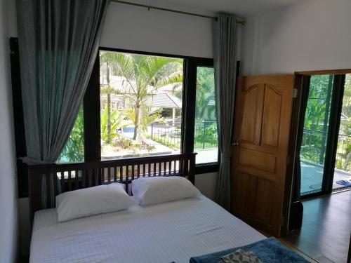 Ban Muang MaiにあるTwin Villaのベッドと大きな窓のある寝室