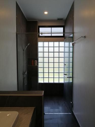 a bathroom with a shower and a glass door at Twin Villa in Ban Muang Mai