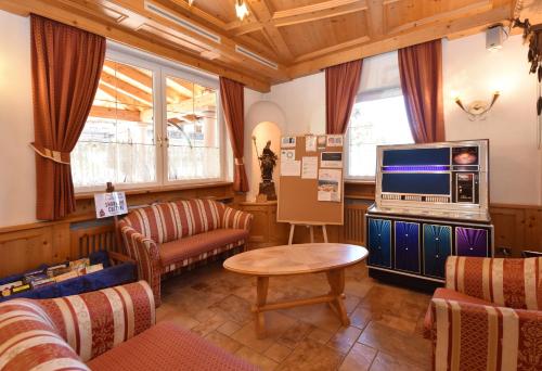 a living room with a tv and a couch and a table at Al Piccolo Hotel in Vigo di Fassa