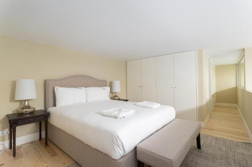 a white bedroom with a large white bed and a chair at FLH Cais Sodré Trendy Duplex in Lisbon