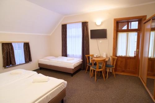 カルパチにあるZielone Wzgórzeのベッド2台とテーブルが備わるホテルルームです。