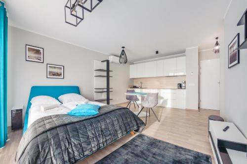 a bedroom with a blue bed and a kitchen at Rezydencja Park, Sun & Snow in Mielno