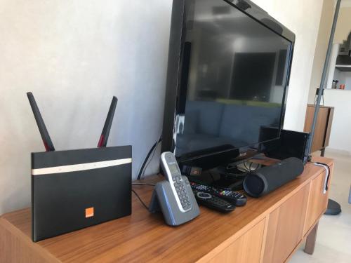 a television and a remote control on a wooden table at Appartement haut standing calme + piscines + WIFI in Asilah