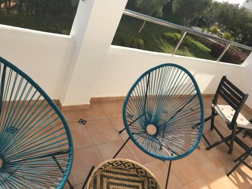 two chairs and a fan sitting on a balcony at Appartement haut standing calme + piscines + WIFI in Asilah