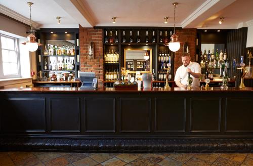 a bar with a man standing behind the bar at Red Lion Hotel by Greene King Inns in Fareham