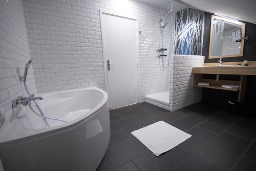 a white bathroom with a tub and a shower at Hôtel Bastide in Onet le Château