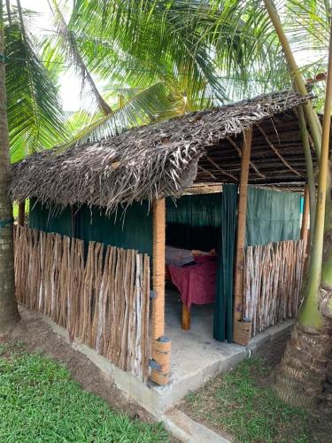 a small hut with a thatched roof and a palm tree at Mahee house in Hiriketiya