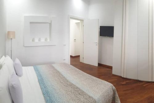 een witte slaapkamer met een bed en een televisie bij Casual Life Suite in Reggio di Calabria
