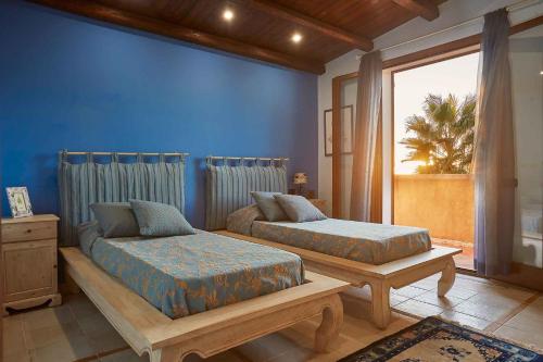 a bedroom with two beds and a blue wall at Scent Selinunte Garden in Castelvetrano Selinunte