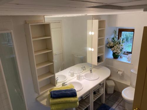 Baño blanco con 2 lavabos y espejo en Herb Cottage en Bradford on Avon
