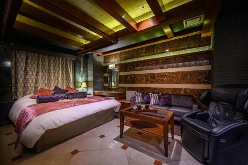 a bedroom with a bed and a couch in a room at HOTEL ZEN Yokohama Hazawa in Yokohama
