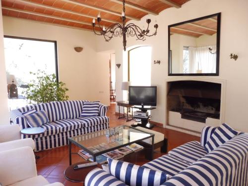 Sala de estar con sofás de rayas azules y blancas y TV en Belvilla by OYO Casa Lourdes, en Sant Miquel de Balansat