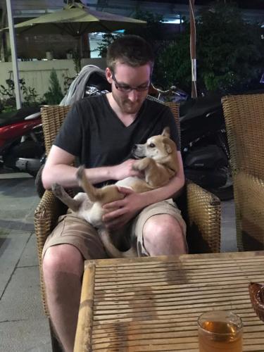 a man sitting in a chair holding a dog at Sunny Riverside Homestay in Hoi An