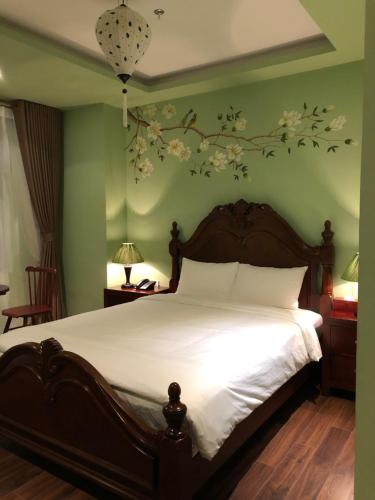 a bedroom with a bed with white sheets and flowers on the wall at Le Grand Hanoi Hotel - The Oriental in Hanoi