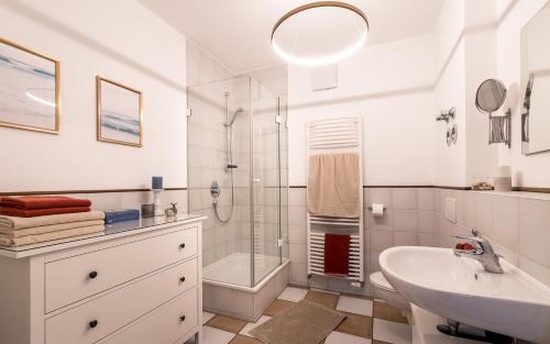 ein weißes Bad mit einem Waschbecken und einer Dusche in der Unterkunft Ferienwohnung Hainzinger in Rettenberg