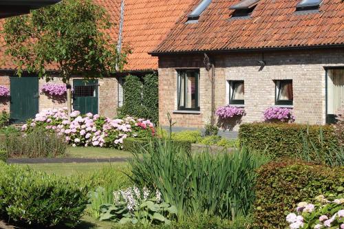 a garden with pink and white flowers in front of a house at Holiday Home De Colve in Bruges