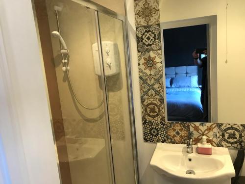 ein Bad mit einer Dusche, einem Waschbecken und einem Spiegel in der Unterkunft Cozy Rooms in Liverpool