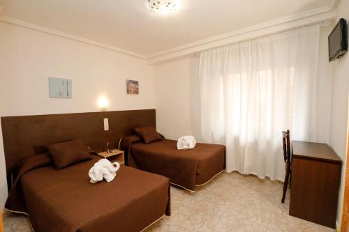 una camera d'albergo con due letti e una televisione di Hostal Conde David a Salamanca