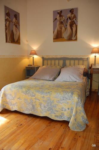 a bed in a bedroom with two pictures on the wall at Le GITE du MAS des CLOTS in Upie