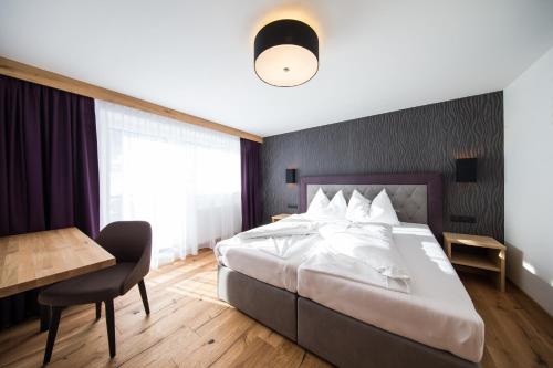 a bedroom with a bed and a table and a desk at Lakeside by A CASA in Sölden