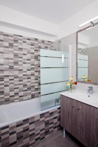 une salle de bain avec un lavabo et un miroir dans l'établissement Residhome Lyon Gerland, à Lyon