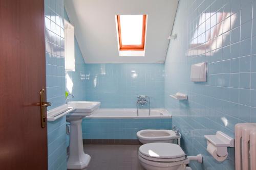 a blue bathroom with a toilet and a sink at Villa Presolana in Castione della Presolana