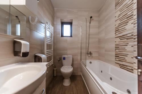 a bathroom with a toilet and a tub and a sink at Luxury Desing Apartment in Piteşti