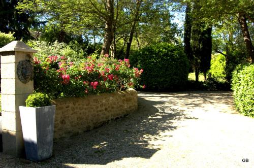 a garden with pink flowers in a stone wall at Le GITE du MAS des CLOTS in Upie
