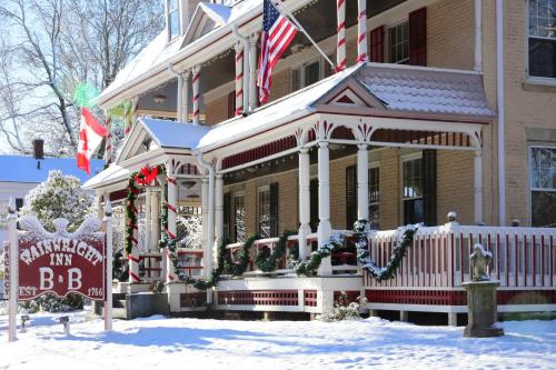 a large house with an american inn sign in the snow at Wainwright Inn in Great Barrington