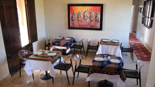 a dining room with tables and chairs and a painting at Villa Diaf Johanne in Aït Ourir