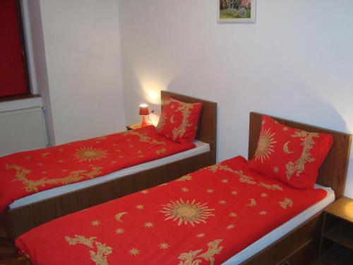 two beds in a room with red sheets at Apartament Miruna Sibiu Filarmonicii in Sibiu