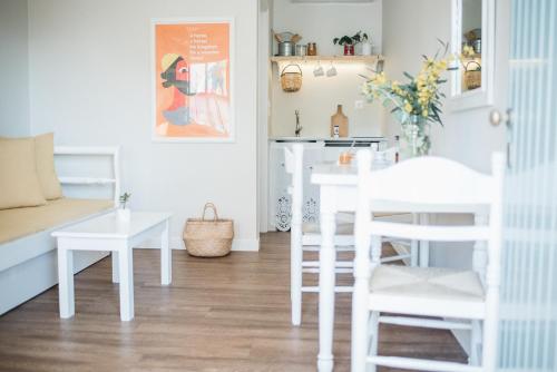 Odyssey Suites في بوروس: غرفة معيشة مع كراسي بيضاء وطاولة