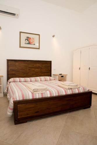 a bedroom with a large bed with a wooden frame at B&B L'Assunta in Alessano