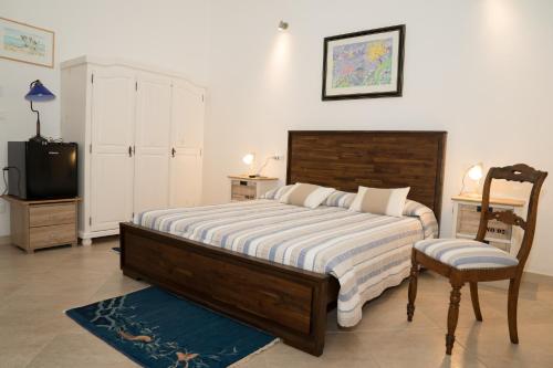 a bedroom with a bed and a tv and a chair at B&B L'Assunta in Alessano