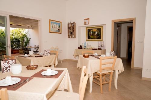 een eetkamer met tafels en stoelen en een kamer met ramen bij B&B L'Assunta in Alessano