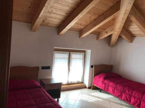 Habitación con 2 camas, ventana y techo de madera. en Agriturismo Monica, en Ronzo Chienis