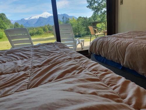 two beds in a room with a view of a mountain at Casa de Campo Buenavista in Pucón