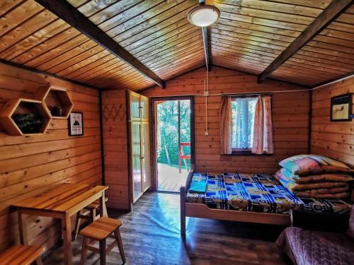 a bedroom in a log cabin with a bed and a table at Domki Pod Wzgórzem in Polańczyk