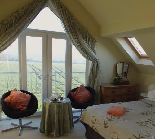 Herb Cottage في برادفورد أون آفون: غرفة نوم بسرير وكرسيين ونافذة