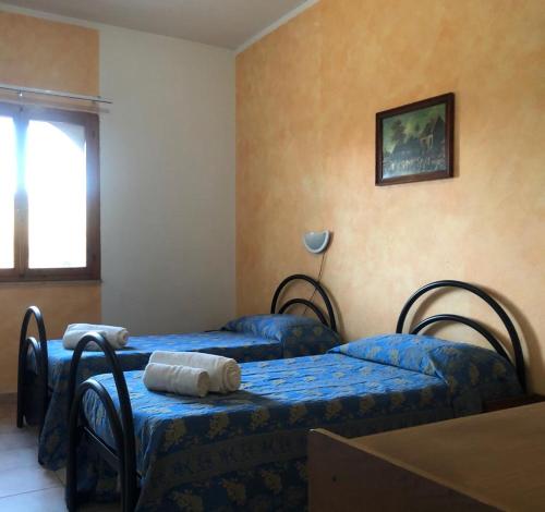 a bedroom with two beds with blue sheets and a window at HOTEL FUNTANA E DONNE in Ottana