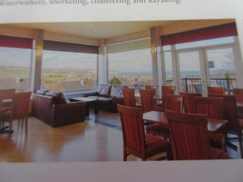 a living room with chairs and a couch and tables at 225 Buttercup Swanage Bay View - Vacation Home in Swanage