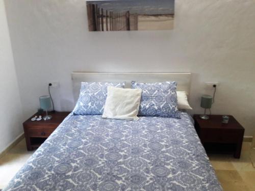 sypialnia z łóżkiem z niebiesko-białą pościelą i poduszkami w obiekcie Punta Paloma w mieście Tarifa