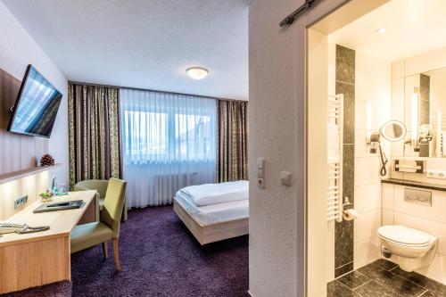 a hotel room with a bed and a bathroom at Hotel Restaurant Krone & Wellness - Schopfheim in Schopfheim